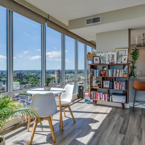 a room with a table chairs and a window with a view of a city