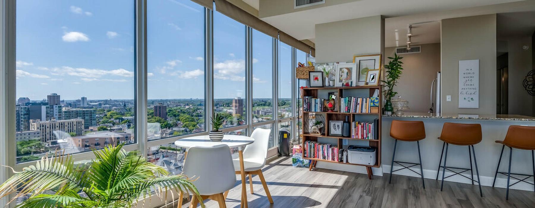 a room with a table chairs and a window with a view of a city