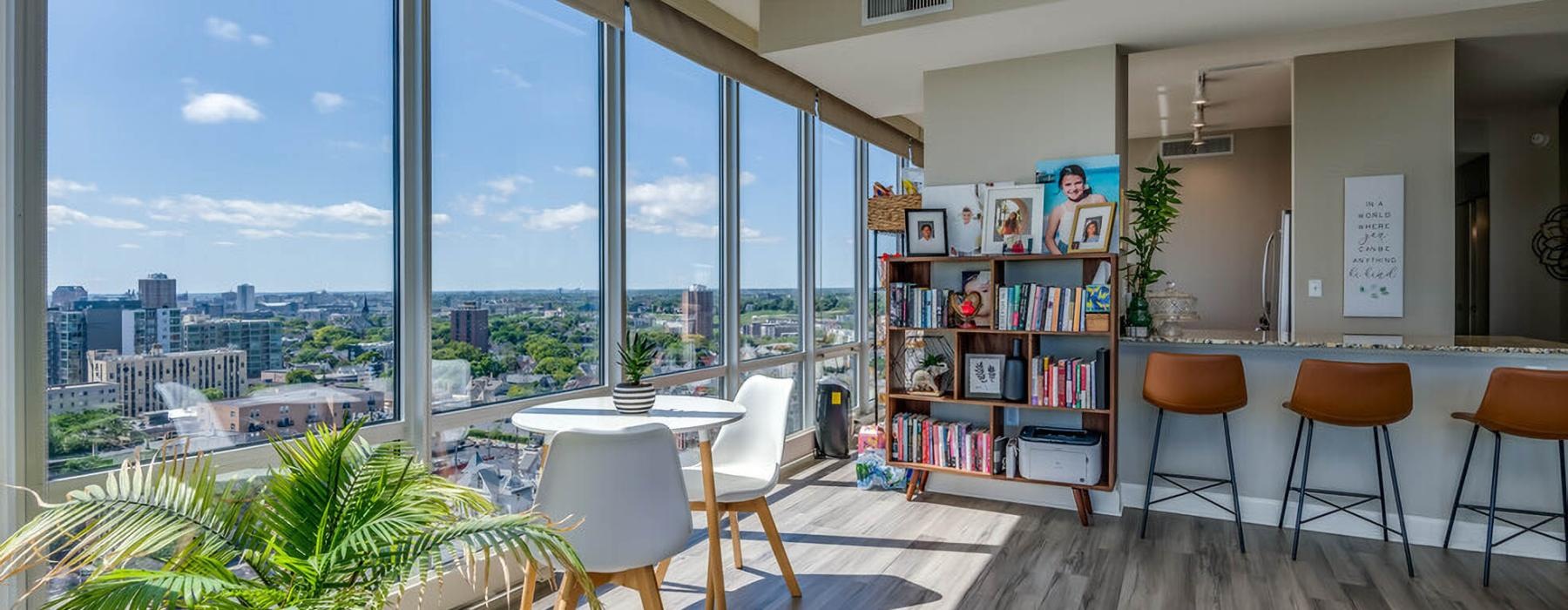 a room with a table chairs and a window with a view of a city